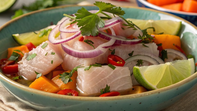 Close-up of a plate of fresh ceviche with lime wedges, cilantro, and onions