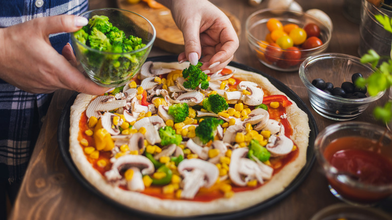 person making veggie pizza