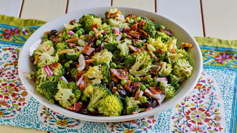 A bowl of raw broccoli salad with red onions and nuts