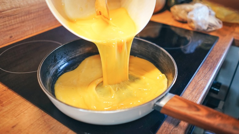 Pouring scrambled eggs into pan