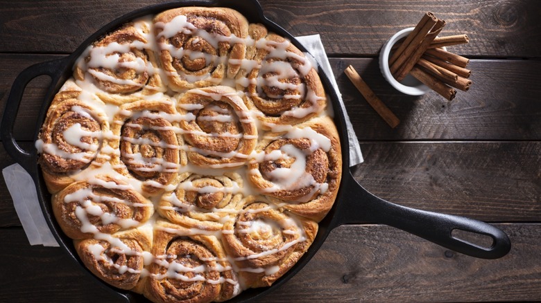 Overview of cinnamon rolls in a cast iron skillet on a wooden table