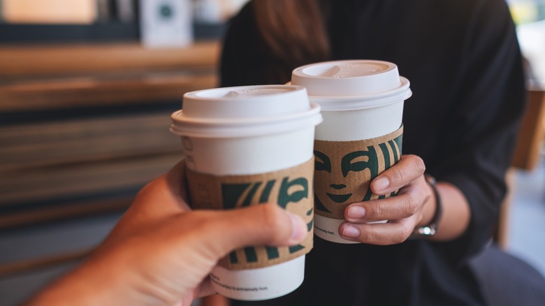 people holding starbucks coffee cups