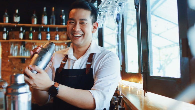 Bartender smiling and shaking cocktail