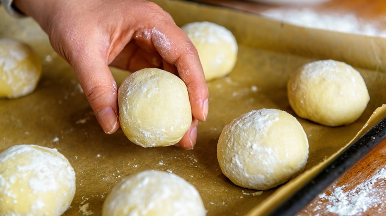 Hand placing bun dough on oven tray