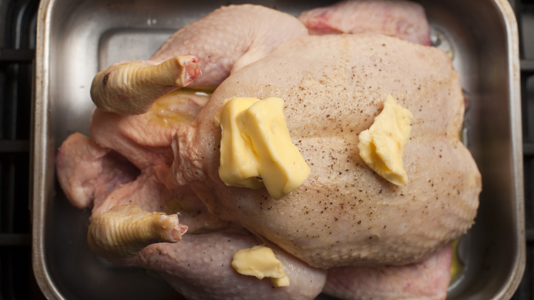 Butter on whole chicken in roasting tray