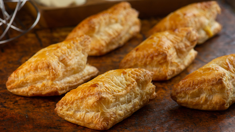 6 golden flaky puffed pastries on a wooden table