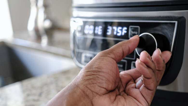 hand adjusting temperature on an air fryer