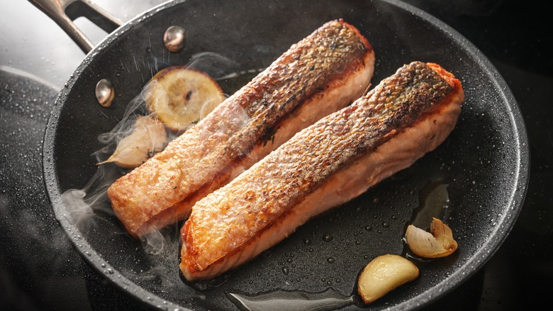 salmon filet in pan with lemon and herbs