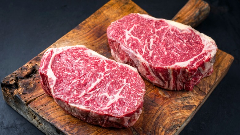 two thick-cut steaks on wooden cutting board