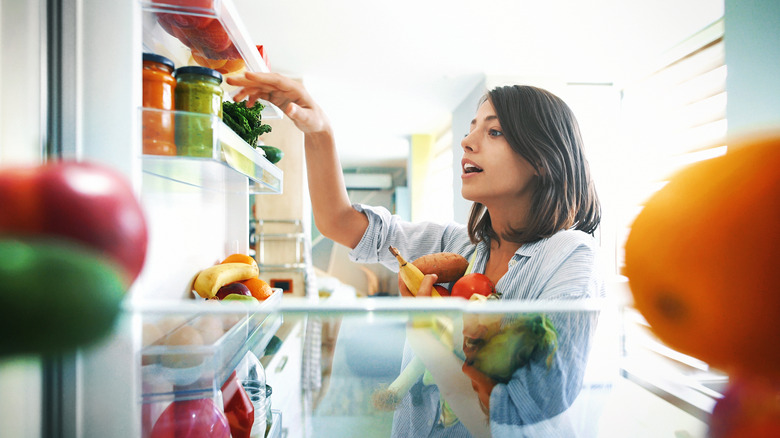 woman grabbing ingredients from fridge