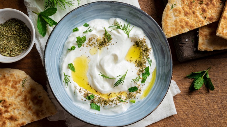 labneh in bowl with oil, herbs, and spices on top