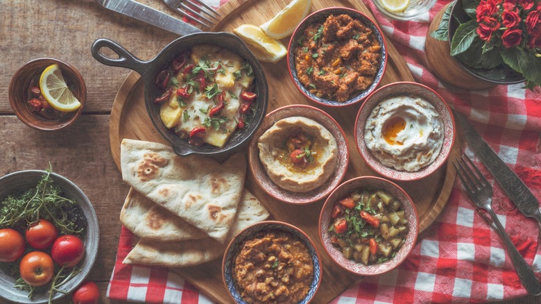 various dips and appetizer items on wooden board