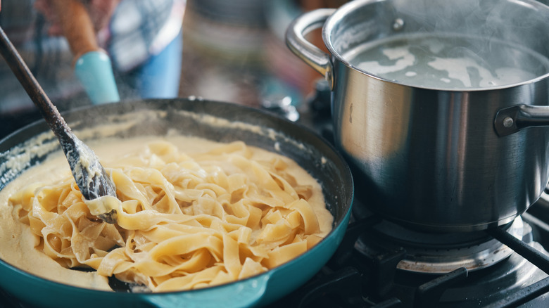 cook stirring homemade alfredo sauce