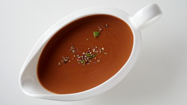 Gravy in gravy boat topped with herbs and spices