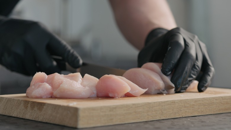 hands cutting chicken 