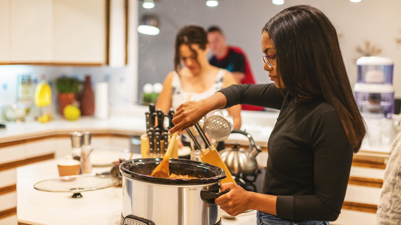 woman stirring slow cooker food