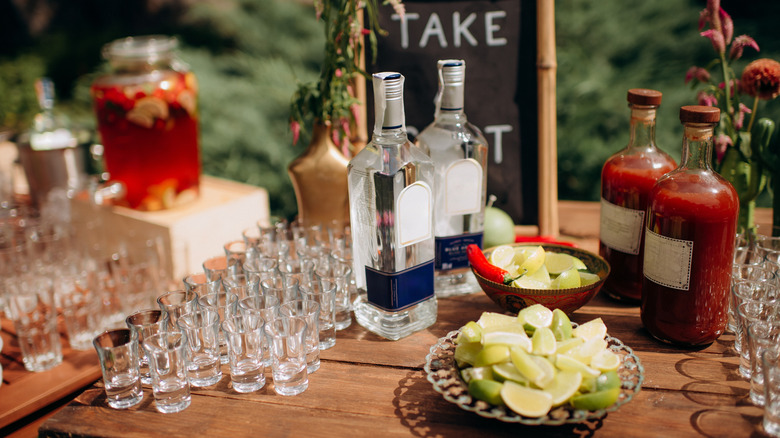 alcohol, shot glasses, and garnishes set up on a table for guests