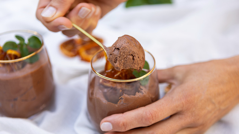 person spooning chocolate mousse 