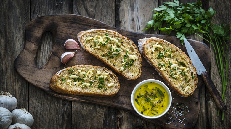 Sliced garlic bread on a cutting board with ingredients