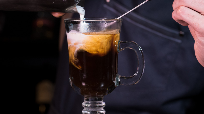 making an Irish coffee with cream pouring onto spoon