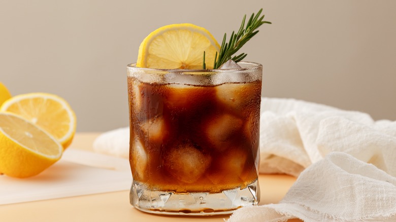 lemonade iced coffee in cup garnished with lemon slice and rosemary 