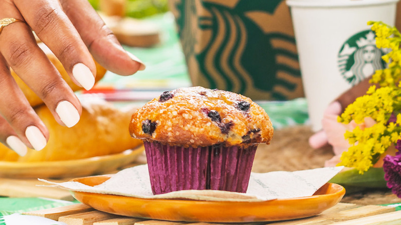 woman reaching for blueberry muffin