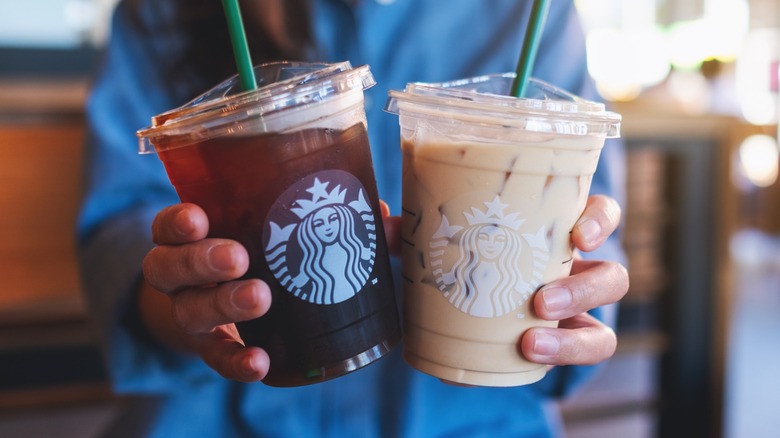 Hands holding two iced Starbucks drinks