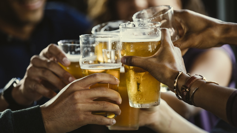 A group clasps their drinks together at the bar