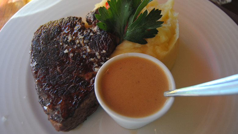 Grilled filet de romsteck sits on a white plate.