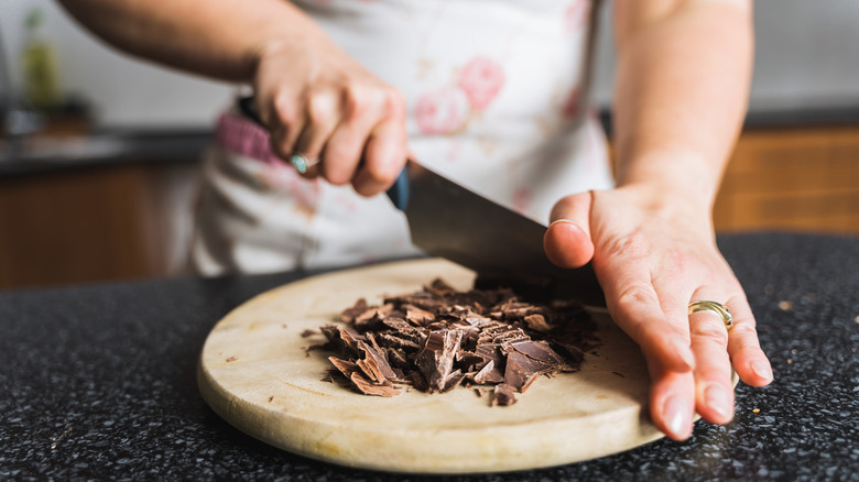 Person chopping chocolate on cutting board