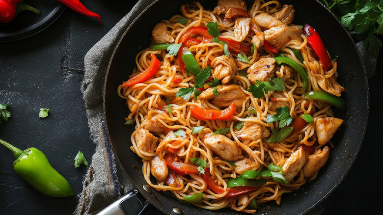 Noodle stir-fry in a pan with peppers and herbs