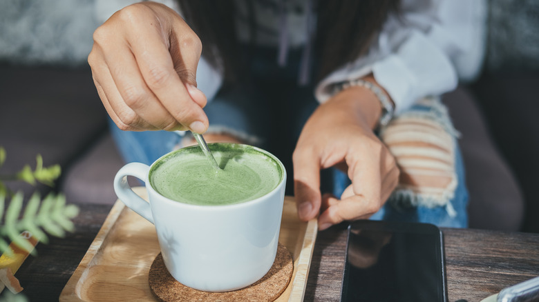 hand stirring matcha latte