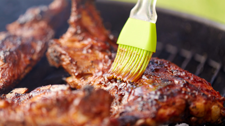 brushing grilled meat with barbecue sauce