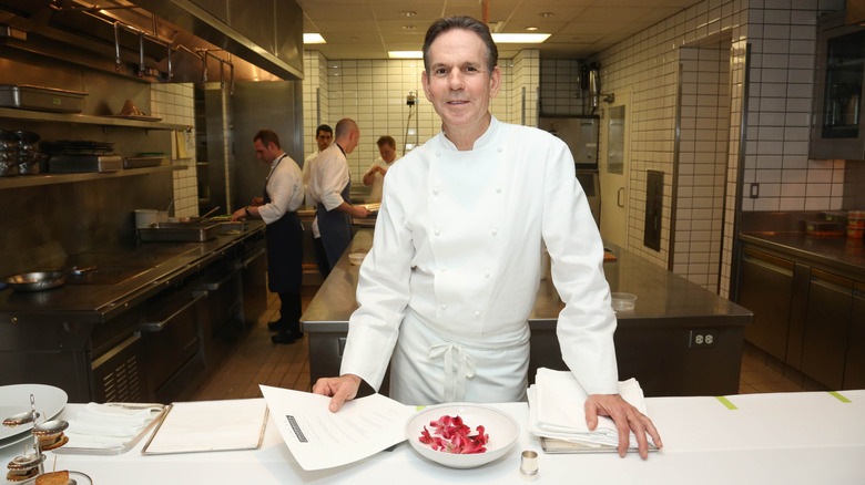 Chef Thomas Keller standing in the kitchen above a plate of food