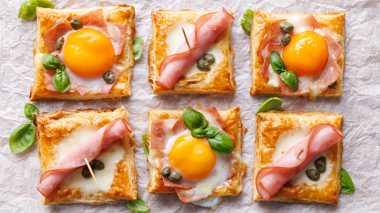 baked puff pastry squares with ham, egg yolks and basil