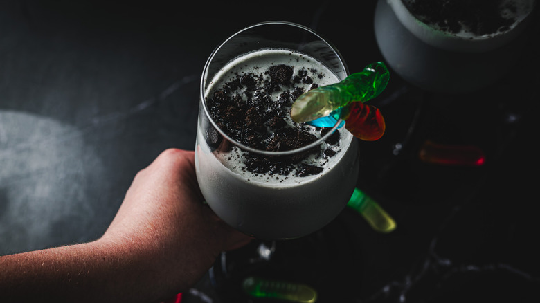 Hand serving cocktail with gummy worms