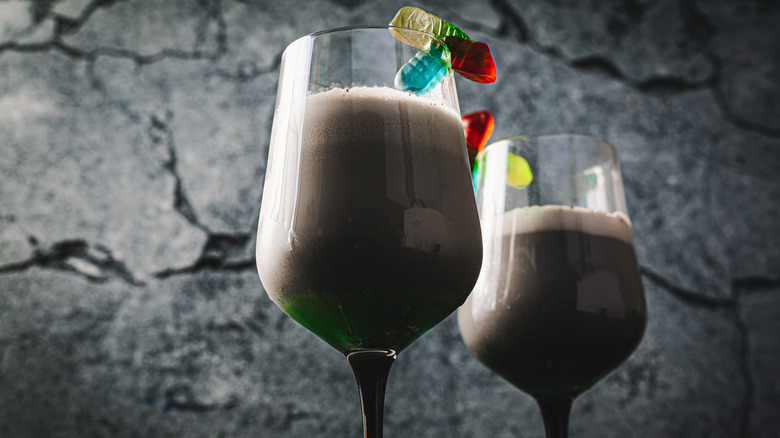 Two glasses of black and green cocktail from below