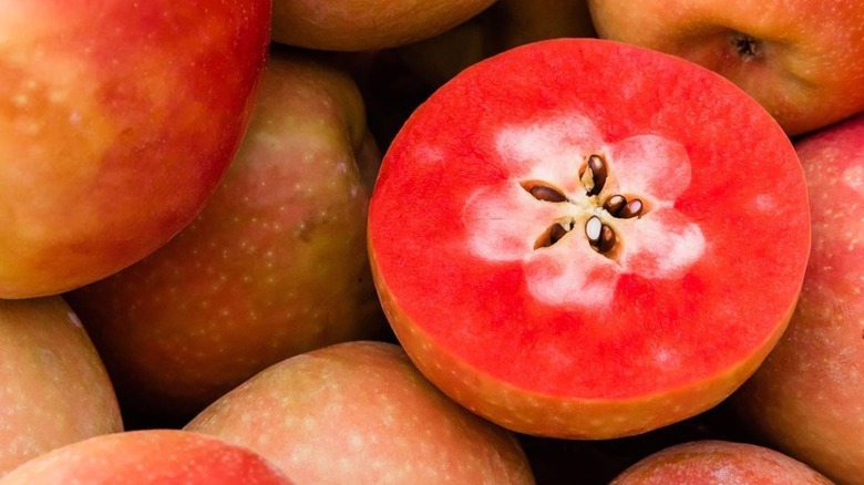 Several whole and one halved Lucy Glo apples