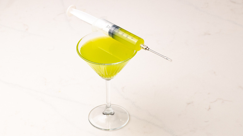 Neon green martini in glass with filled syringe