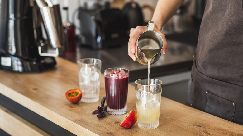 person pouring simple syrup into drink