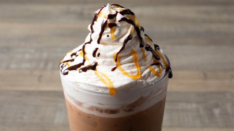 Iced coffee topped with whipped cream and mocha drizzle