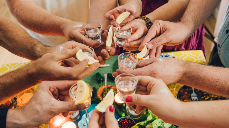 Hands holding shot glasses 