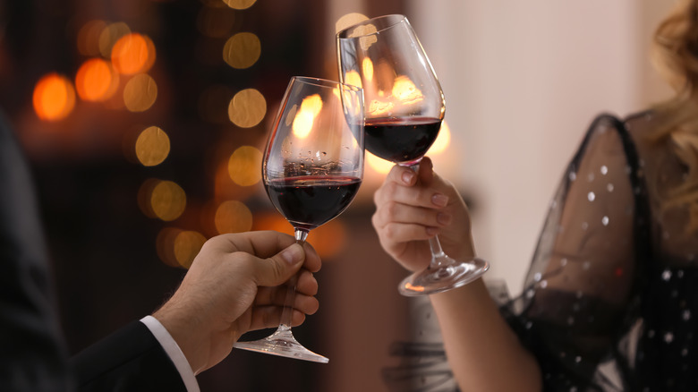 man and woman cheering wine glasses