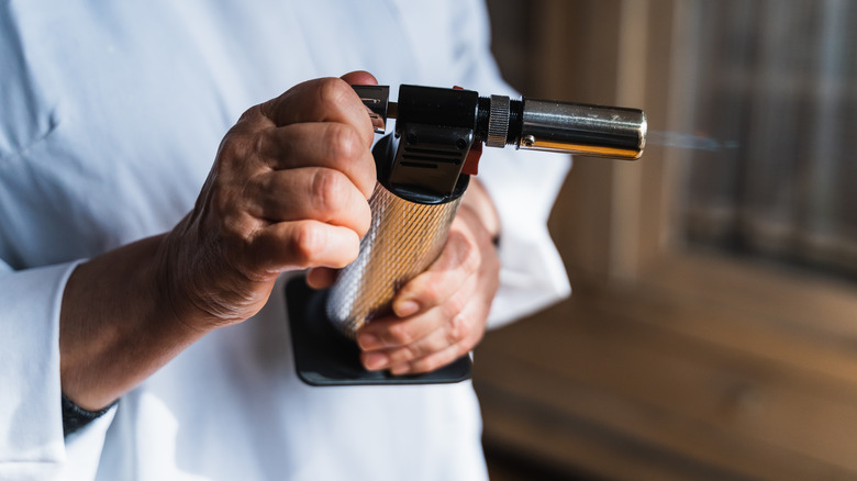 Person holding blow torch