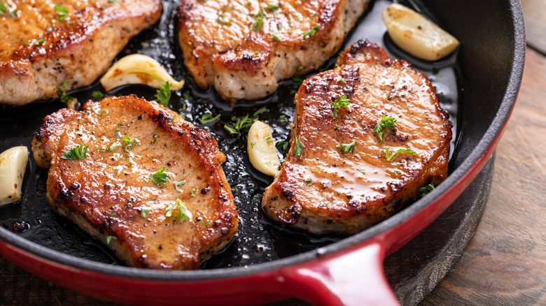 Pork chops searing in a cast iron pan