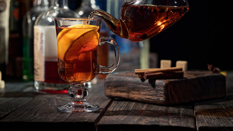 Teapot pouring into hot toddy mug