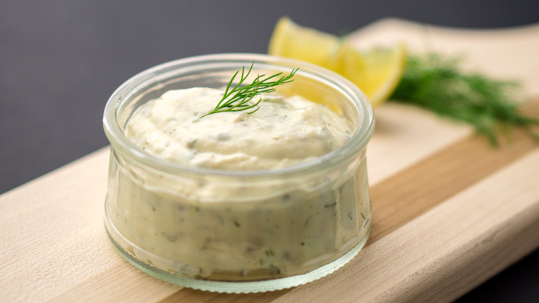 Ramekin of tartar sauce on cutting board 