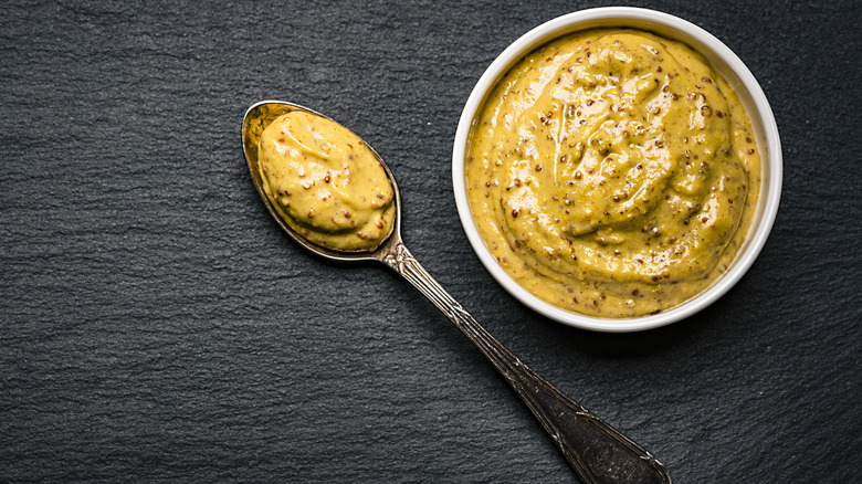 A bowl and a spoon filled with mustard