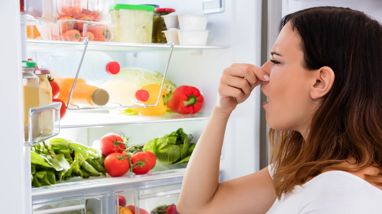 Woman pinching nose due to fridge smell