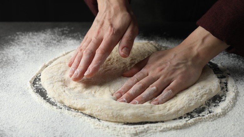 Hands shaping pizza dough